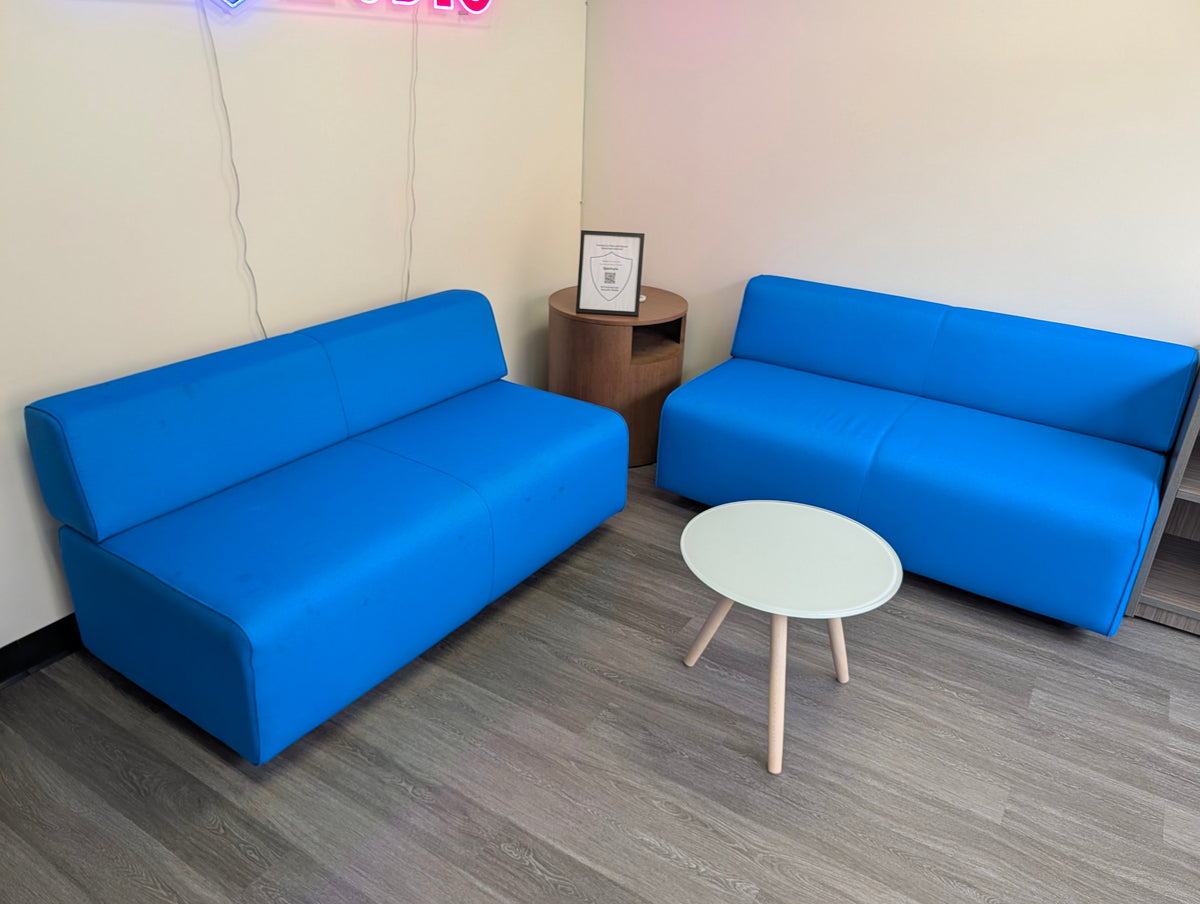 Two blue armless lounge loveseats with side tables